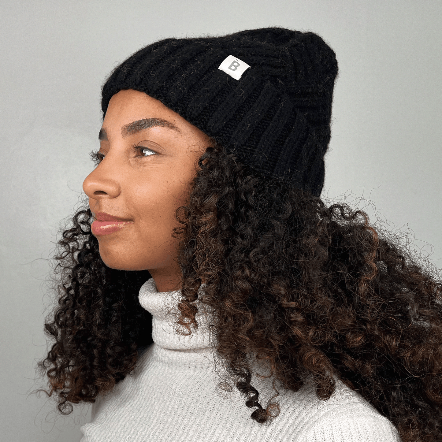 bonnet noir doublé de soie sur un mannequin aux cheveux frisés