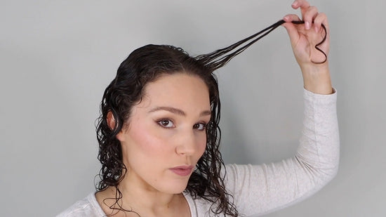 woman styling her dark brown, wavy hair with Bouclème products